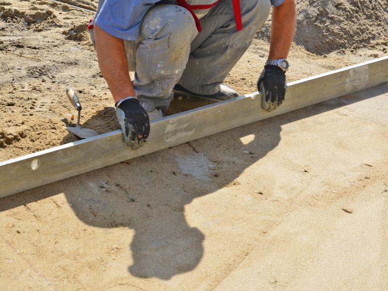 Screeding a precise layer of bedding sand to create a perfectly level surface for pavers.