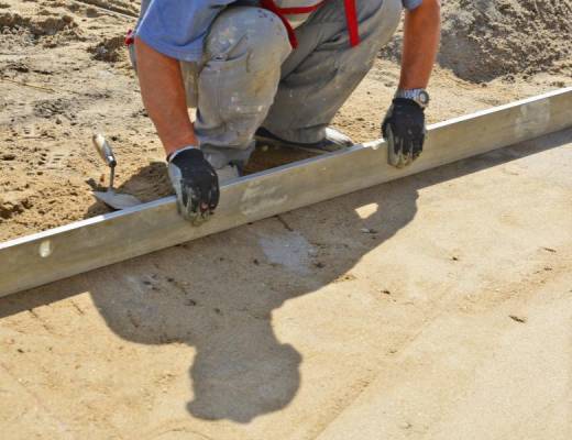 Screeding a precise layer of bedding sand to create a perfectly level surface for pavers.
